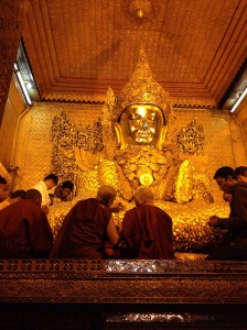 Monks applying gold leaf to the image of Buddha in Mandalay