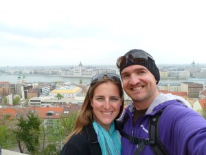 Two photos looking down on a city. The top photo is overlooking the main market square in Marrakech. The bottom photo is a selfie overlooking Budapest